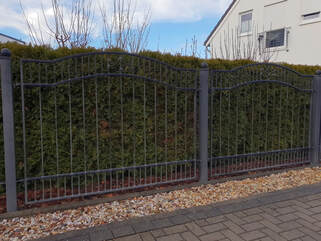 This is an aluminum fence up against some bushes. It is a beautiful design and very high quality. Great for homeowners looking for design and security, but maybe without the privacy.